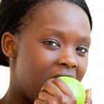 Food Young woman biting into a green apple.