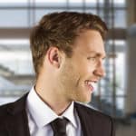Jesse’s Story – thumbnail Young man in a suit smiling looking off camera
