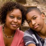 Mike’s Story – thumbnail A Woman and a teen boy closely sitting and smiling at the camera