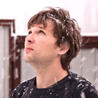 Young man looking into the sky while it's snowing