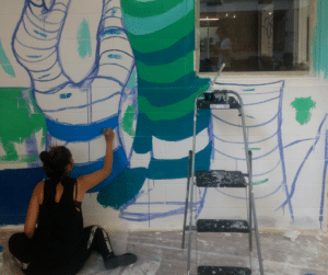 Indoor Mural 03 A resident of Eva's beginning to paint a tree.