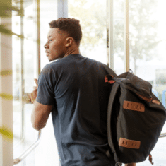 A young man exiting a building with a backpack on.A young man exiting a building with a backpack on.