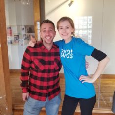 A young woman in an Eva's t-shirt standing with a fellow volunteer happily.