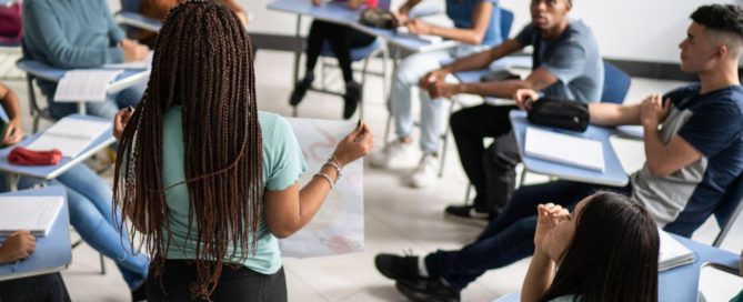 A young person presenting their poster at a workshop to students